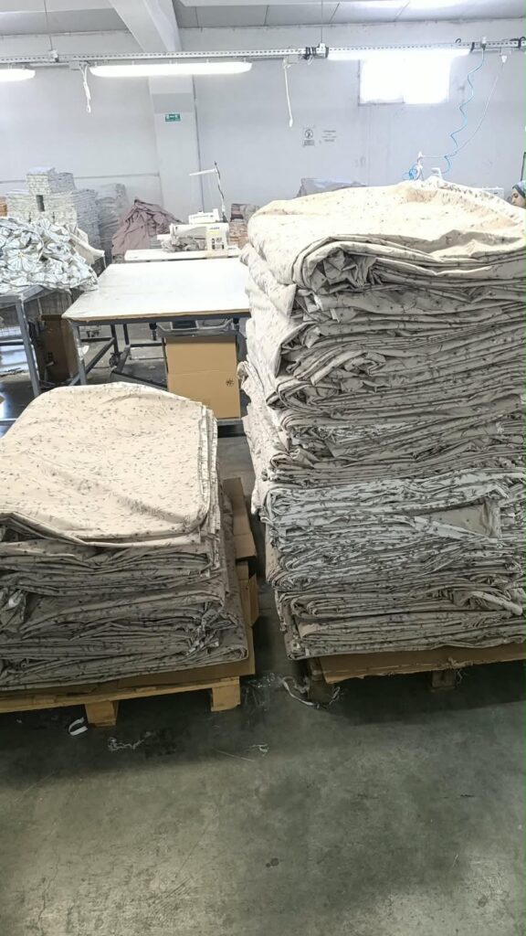 Dikiş at&ouml;lyesinde paletler &uuml;zerinde istiflenmiş desenli tekstil &uuml;r&uuml;nleri