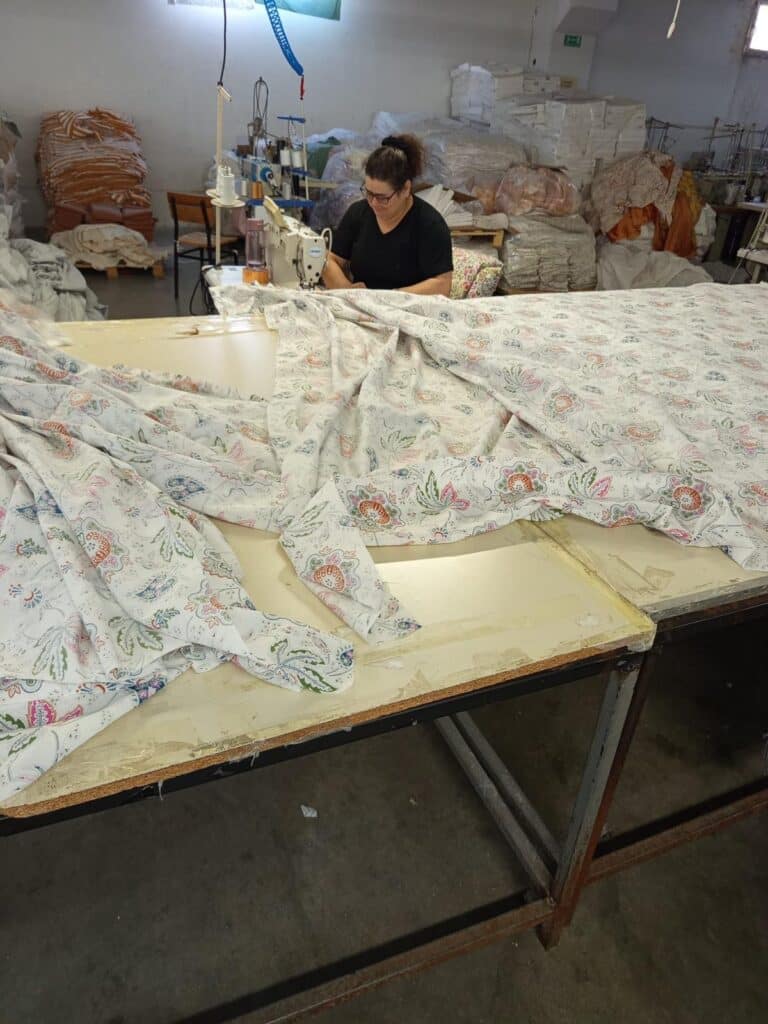 Dikiş makinesinde renkli &ccedil;i&ccedil;ek desenli kumaşın işlendiği &uuml;retim aşaması