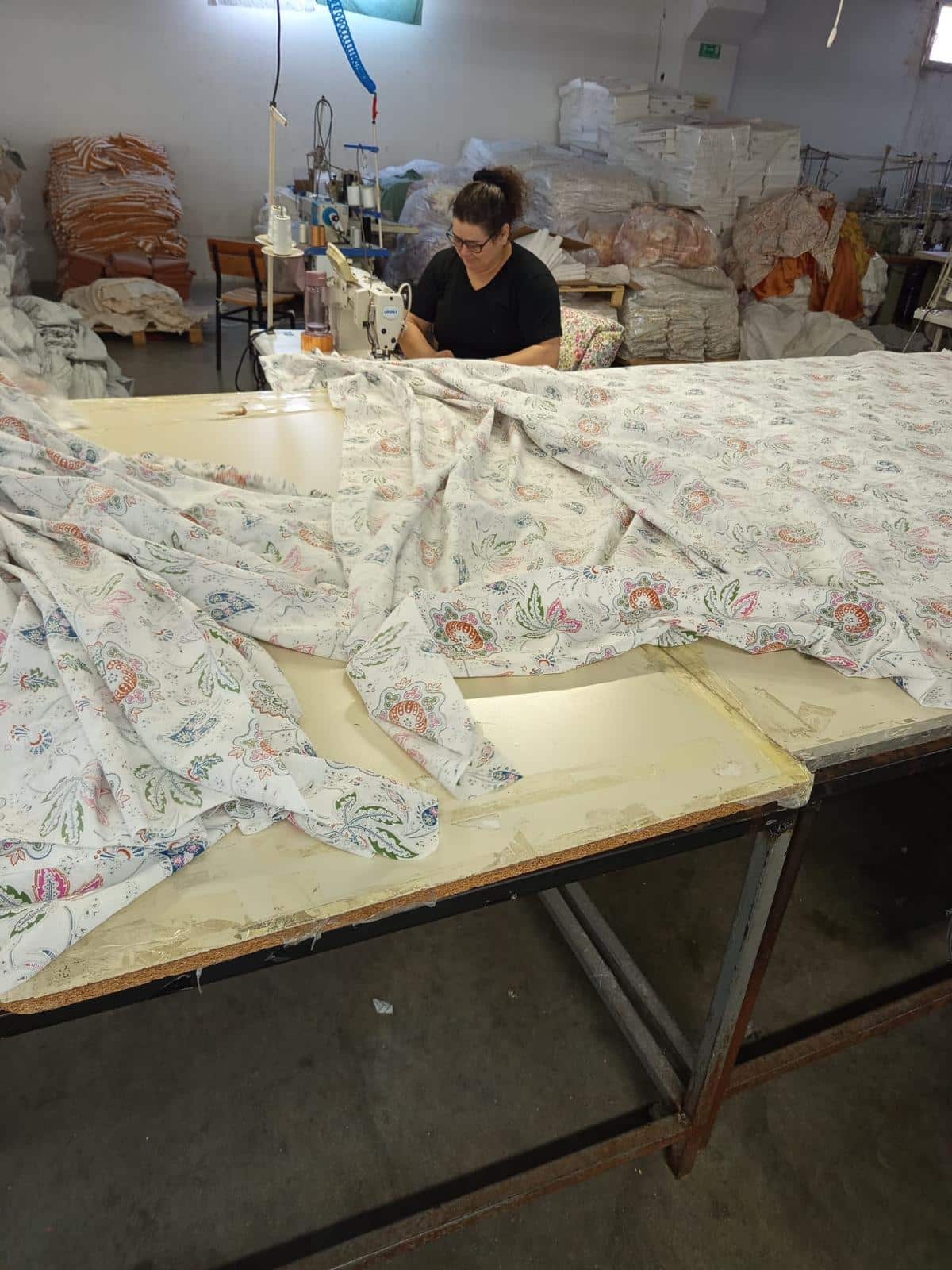 Dikiş makinesinde renkli &ccedil;i&ccedil;ek desenli kumaşın işlendiği &uuml;retim aşaması