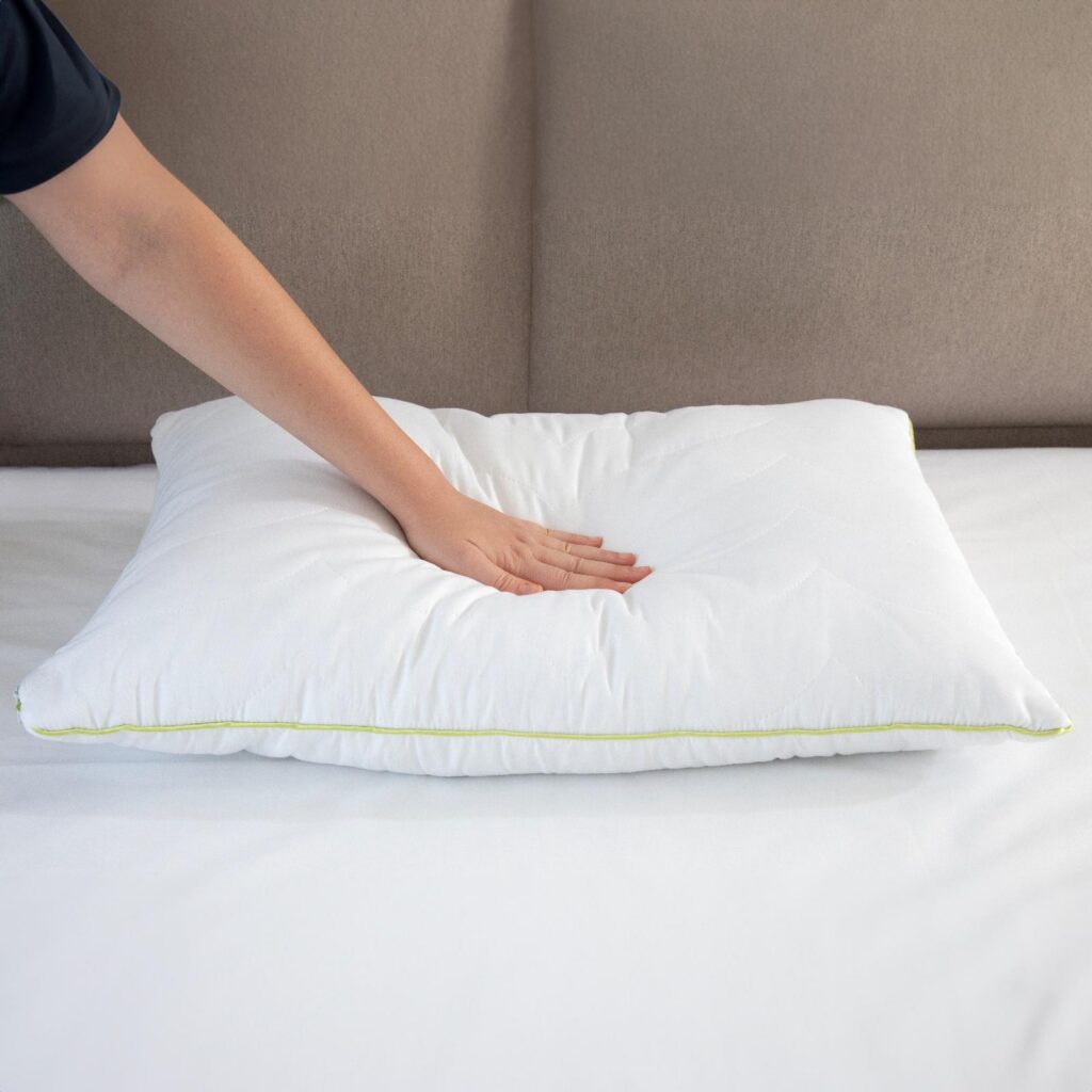 White quilted pillow being pressed by hand
