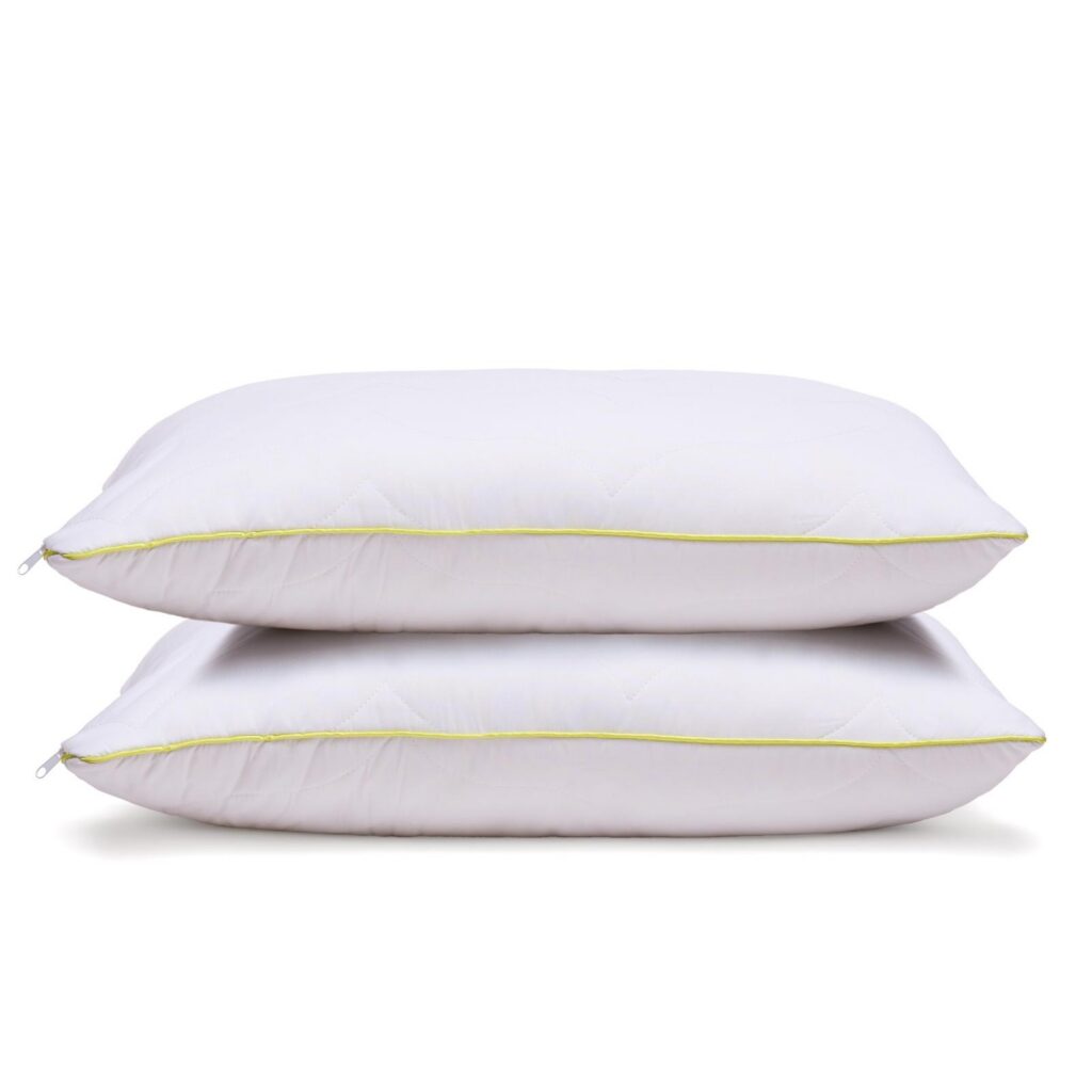 Two white quilted pillows with yellow-green piping on a white background