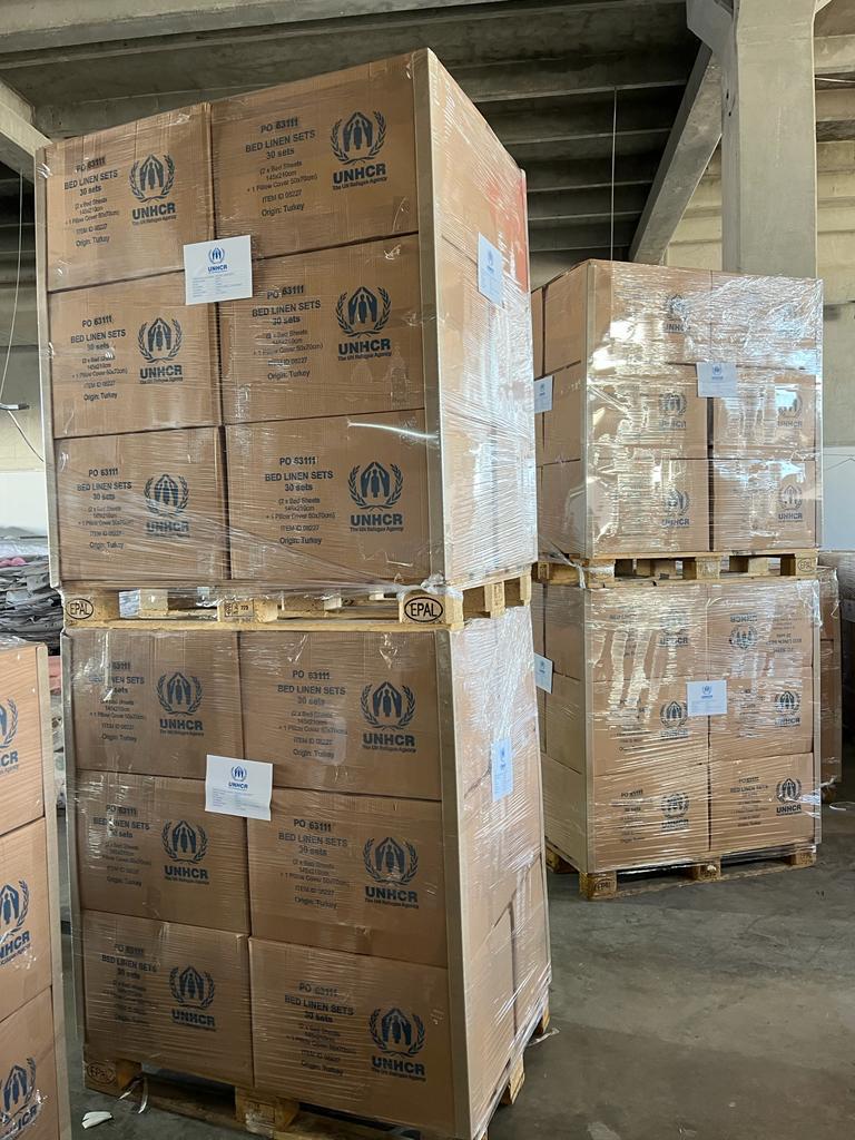 Scatole di completi letto con scritta UNHCR impilate su pallet in magazzino