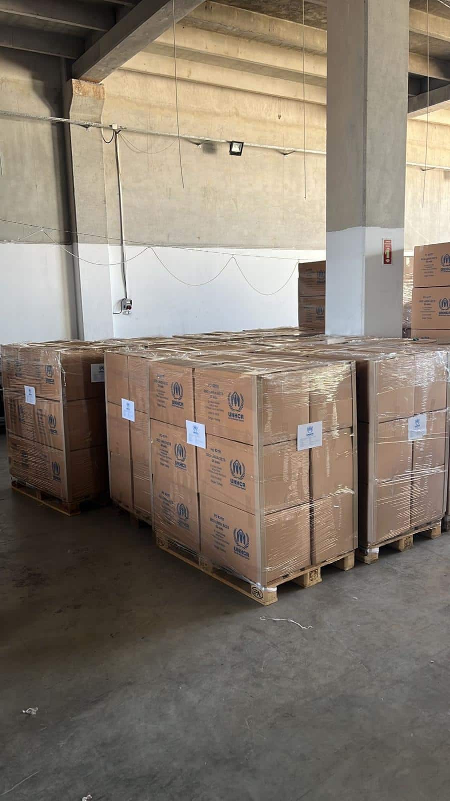 Scatole con scritta UNHCR avvolte in film estensibile su pallet in magazzino