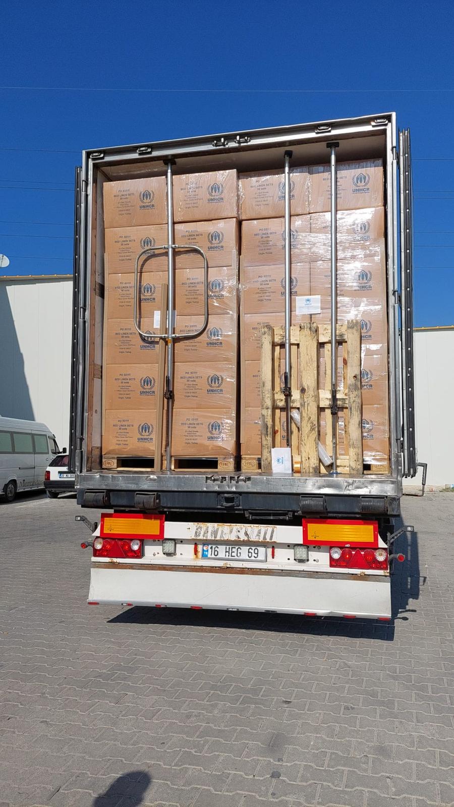 Vista posteriore di un camion carico di scatole su pallet con scritta UNHCR